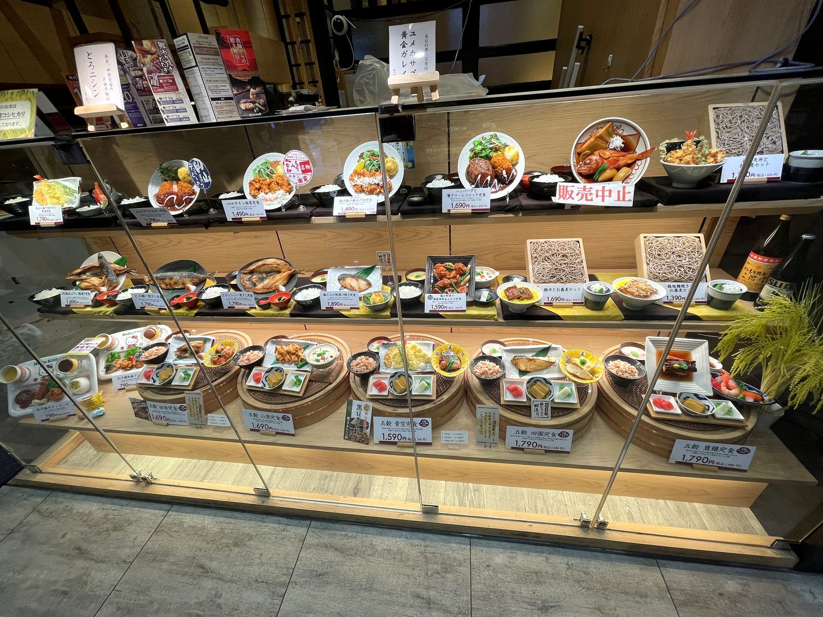 五穀のショーケースの拡大。五穀定食など各メニューの食品サンプルと価格札が並んでいる