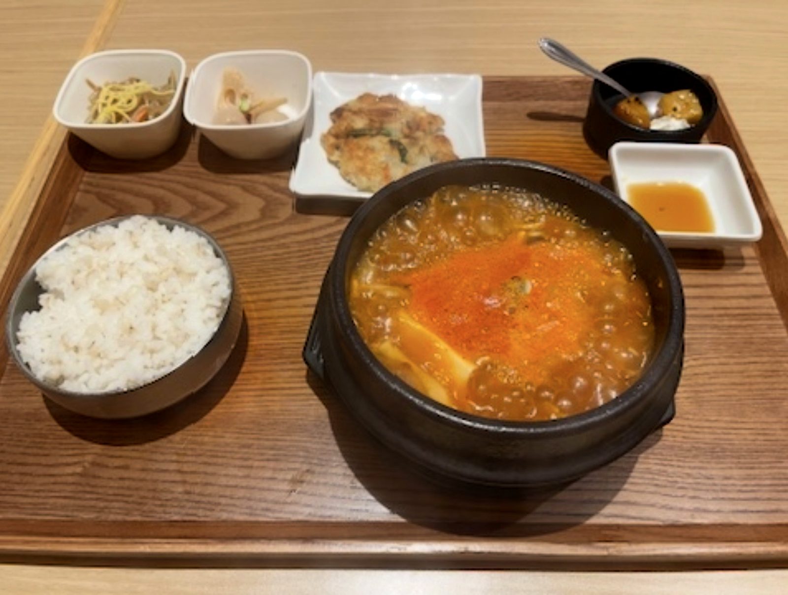 韓美膳のスンドゥブセット全体。麦ご飯、スンドゥブの器、小鉢2つ、チヂミ、デザートが木のトレイに並ぶ
