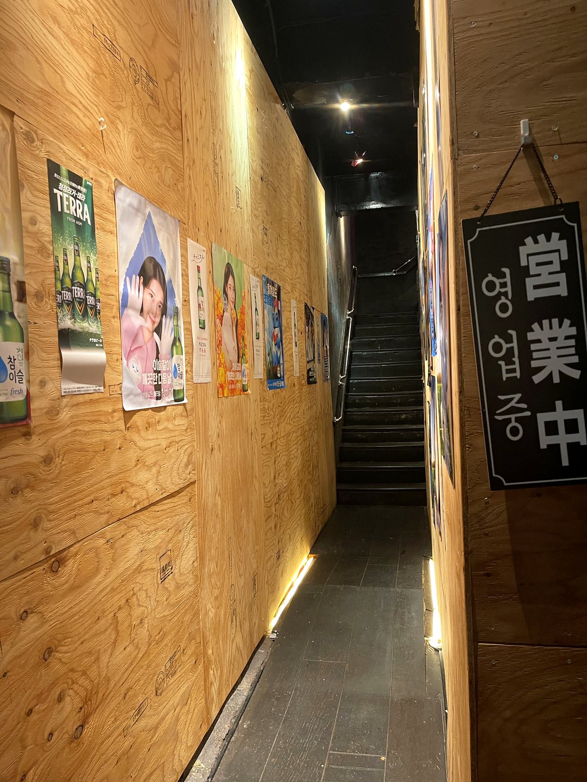 店内へ続く階段。壁には韓国の焼酎ポスターが並ぶ