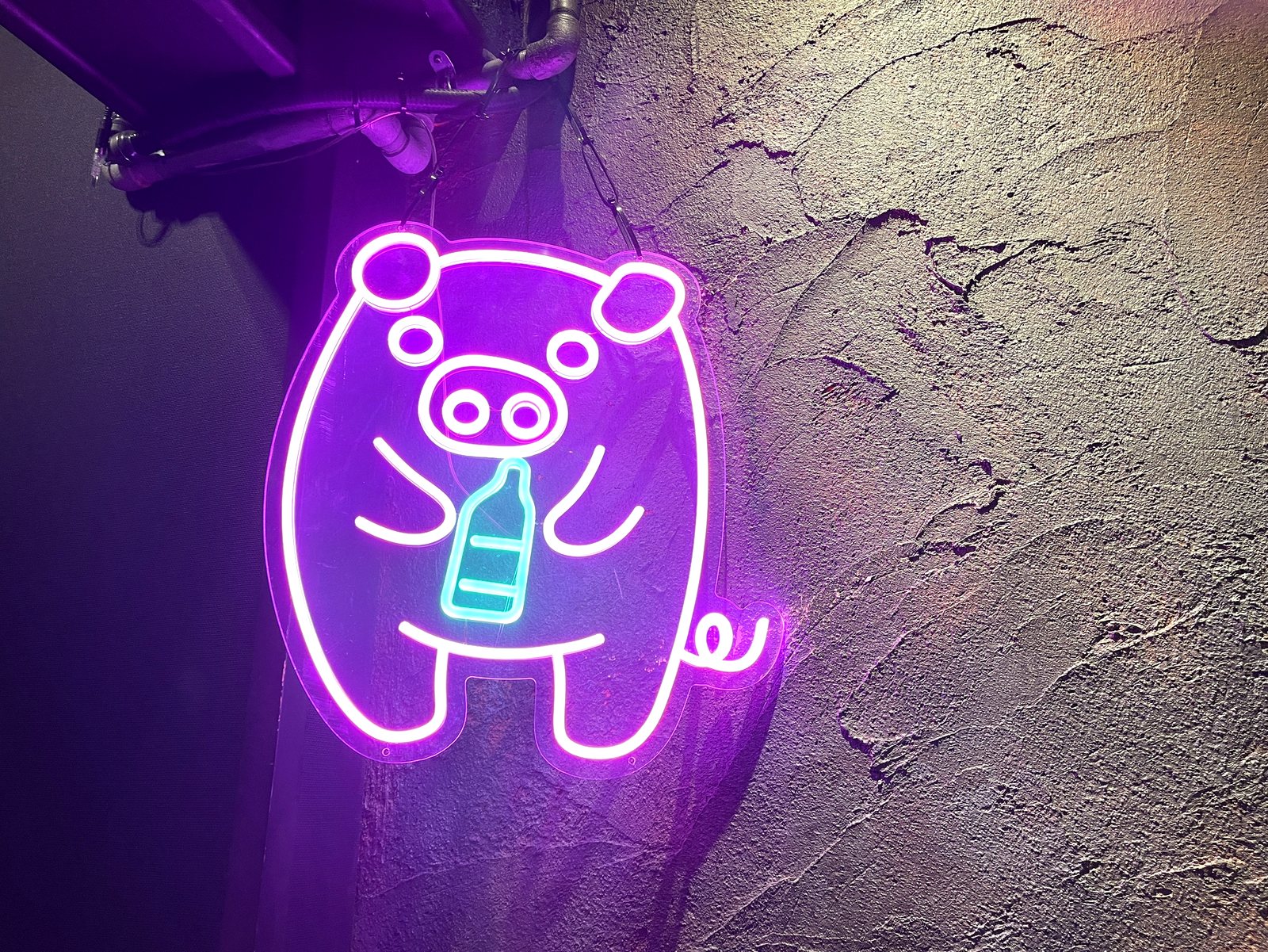 店内の壁に光る、瓶を持った豚のネオンサイン
