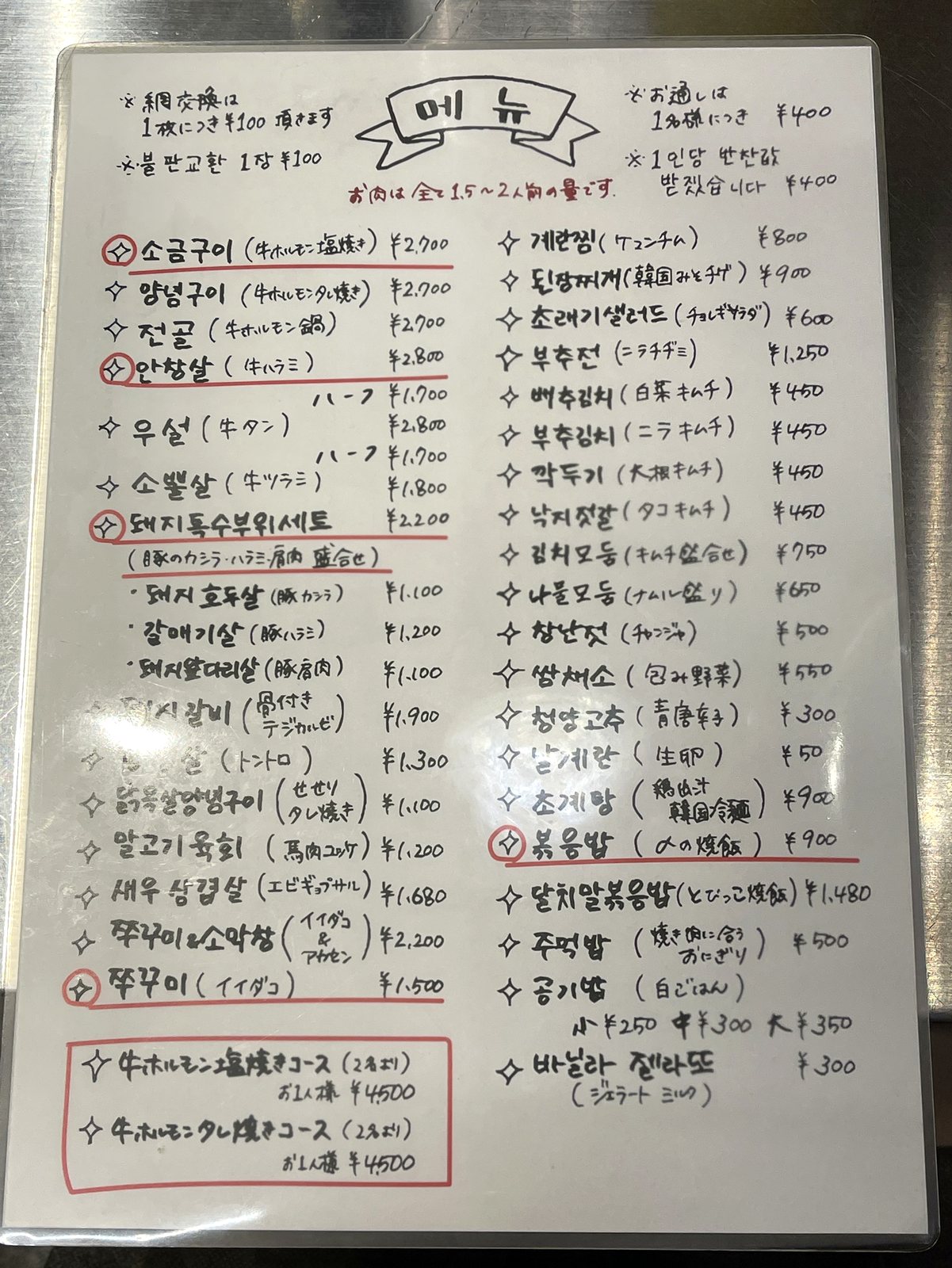手書きの料理メニュー。ホルモンやイイダコ、〆の焼飯などが並ぶ