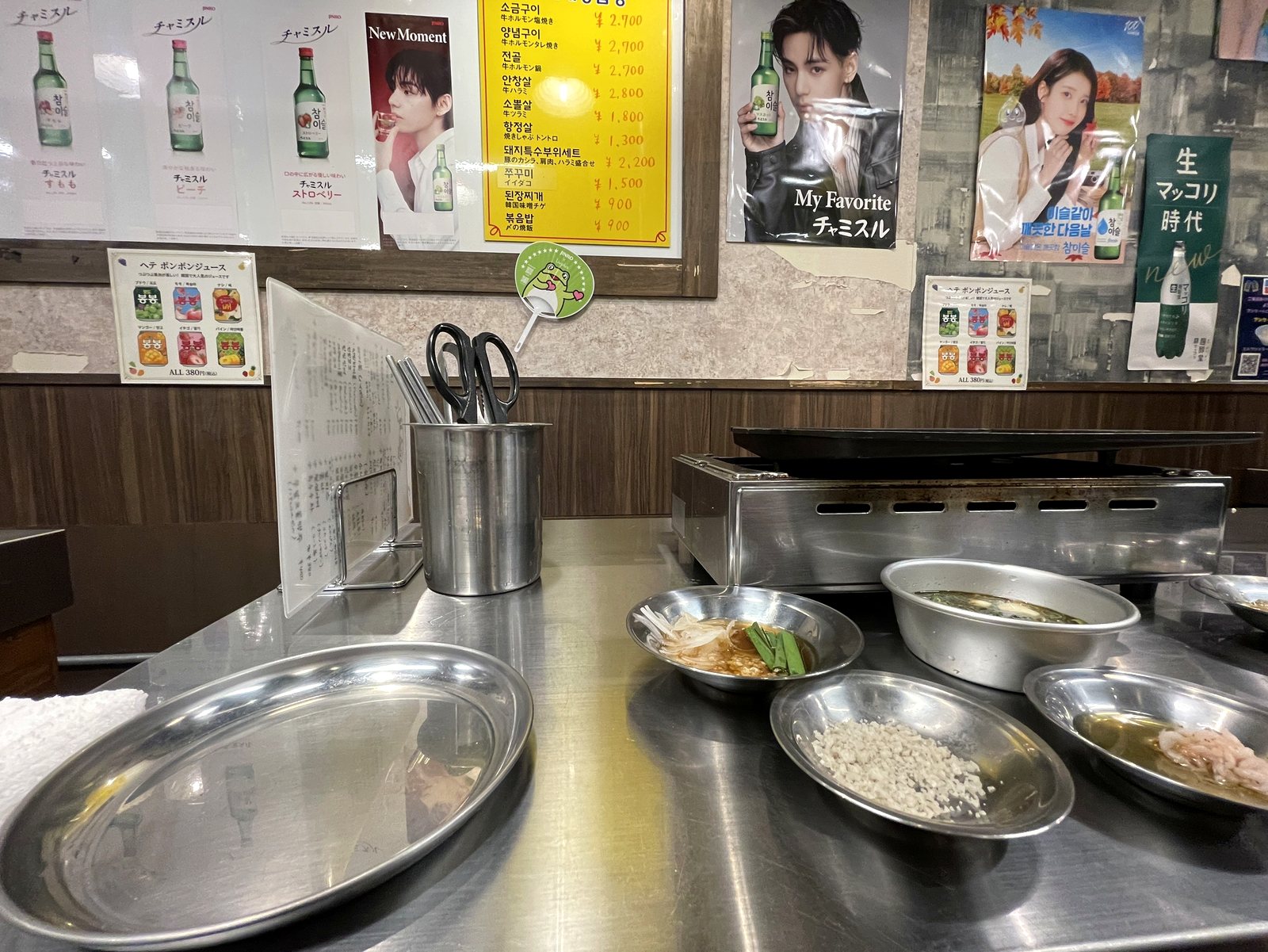 鉄板と小皿が並ぶカウンター席。壁には韓国焼酎のポスター