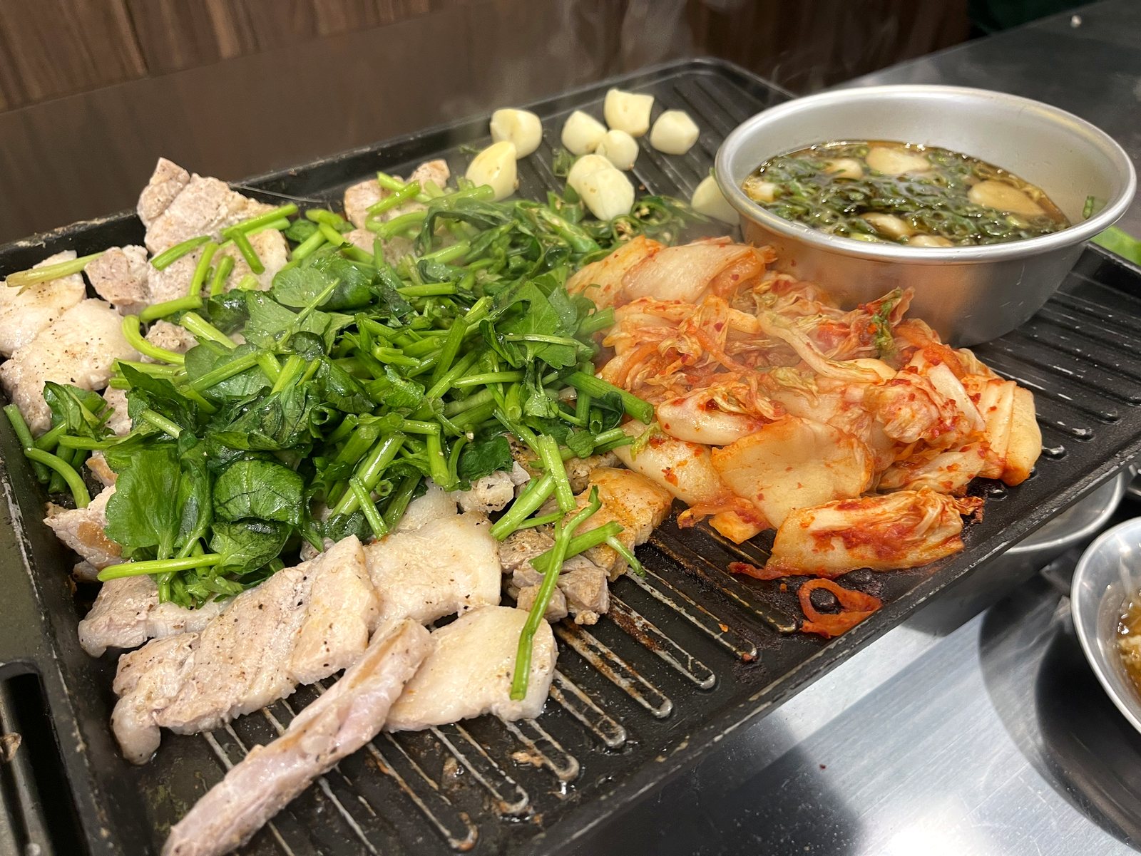 豚肉の上に山盛りになったミナリと、焼かれているキムチ