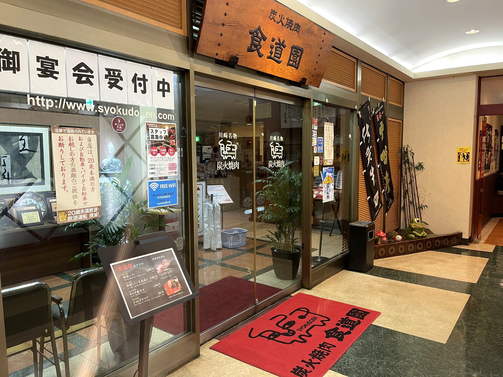 炭火焼肉 食道園の入口。木の看板と赤いマット
