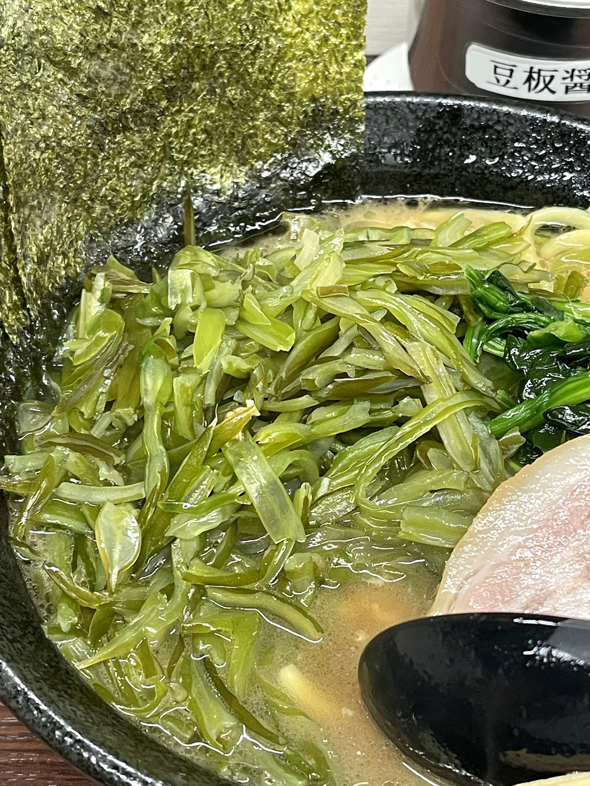 茎わかめのクローズアップ。シャキシャキ感が伝わるアップで、豆板醤の瓶も写り込んでいる