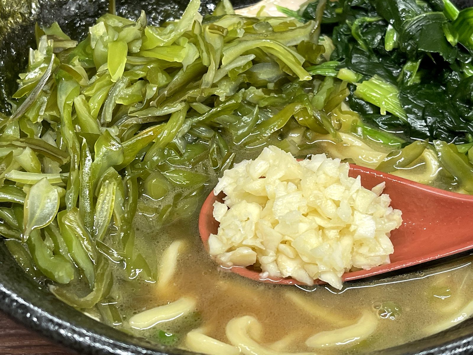 刻みニンニクをレンゲに乗せてラーメンに加える瞬間