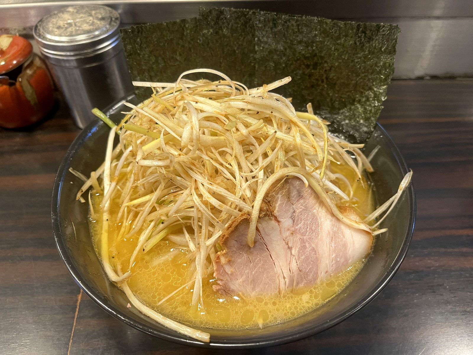 ラーメン道楽のネギラーメンの全体。山盛りの白髪ネギ、大きめのチャーシュー、海苔がのった濃厚豚骨スープの一杯
