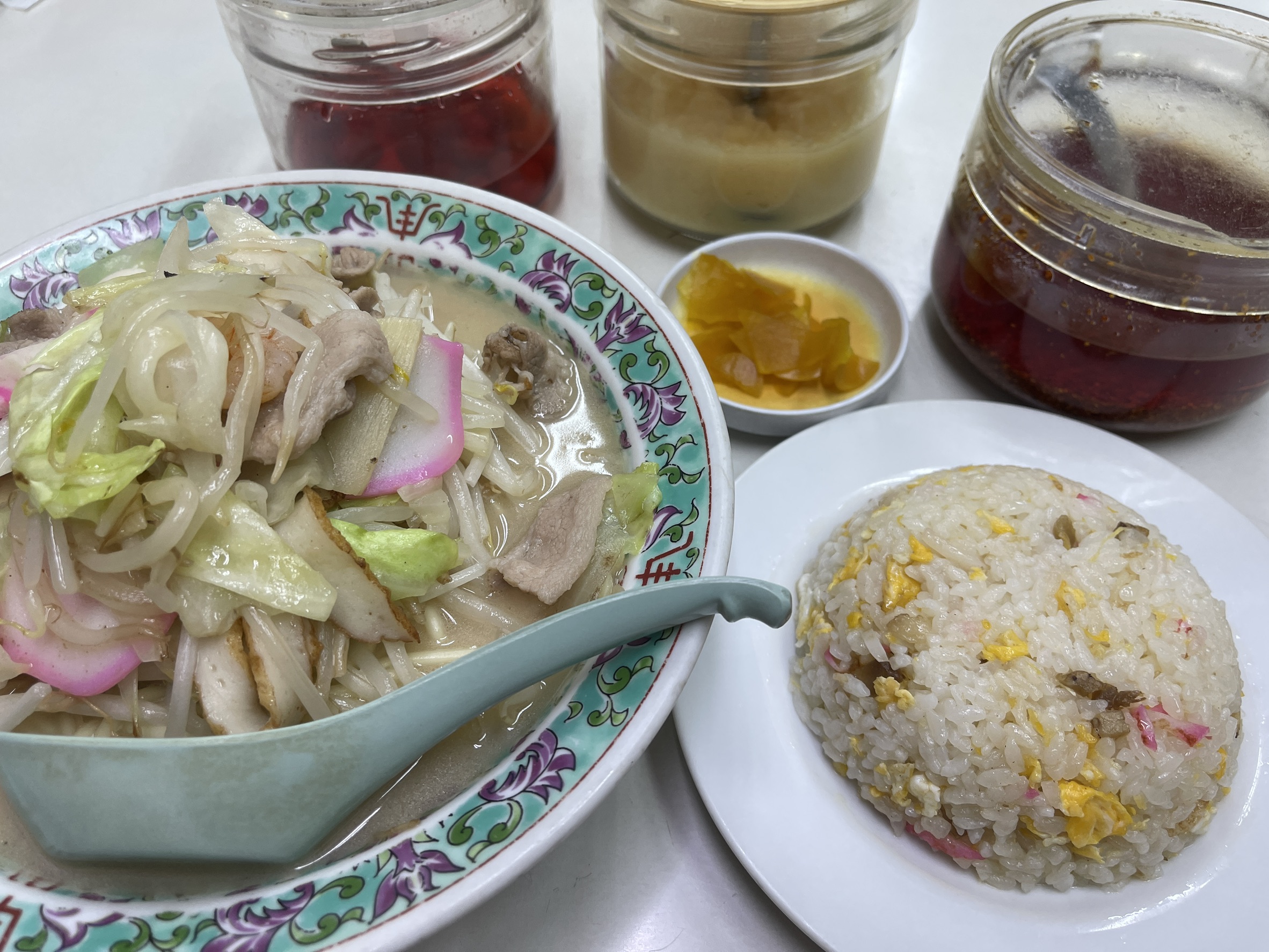 西海の長崎ちゃんぽん。白濁した豚骨ベースのスープに、たっぷりのもやしとキャベツ、ピンクと白のかまぼこ・ナルト、豚肉が盛られ、右手前に半チャーハンの小皿が添えられている