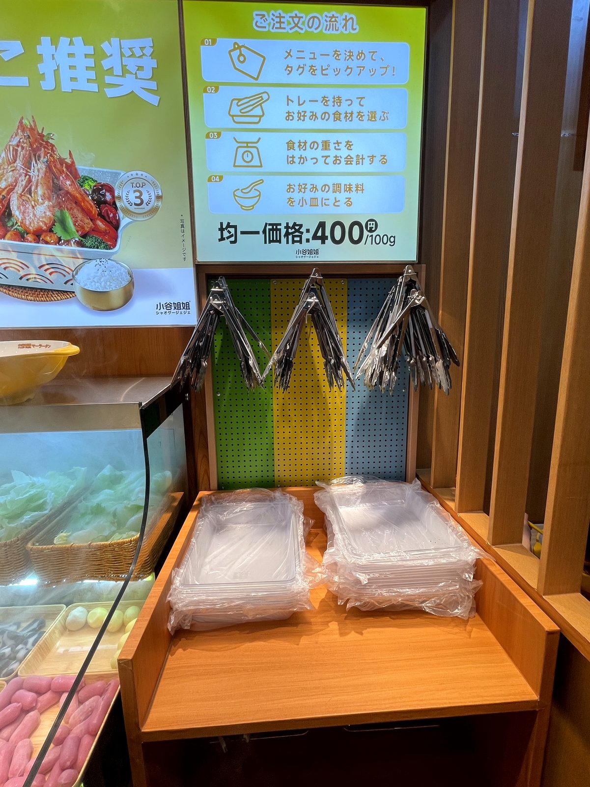 小谷姐姐 川崎店の注文方法の案内看板。トレーを持って具材を選ぶ量り売りスタイルが説明されている