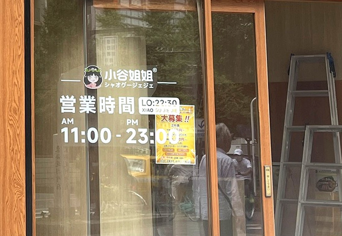 小谷姐姐の入口ガラスに貼られたロゴと営業時間の案内。AM11:00からPM23:00、ラストオーダー22:30