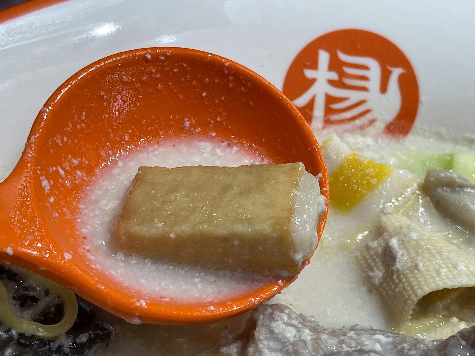 レンゲに乗せた白い四角いブロック状の練り物。外側はかまぼこで中にお餅が入っている具材
