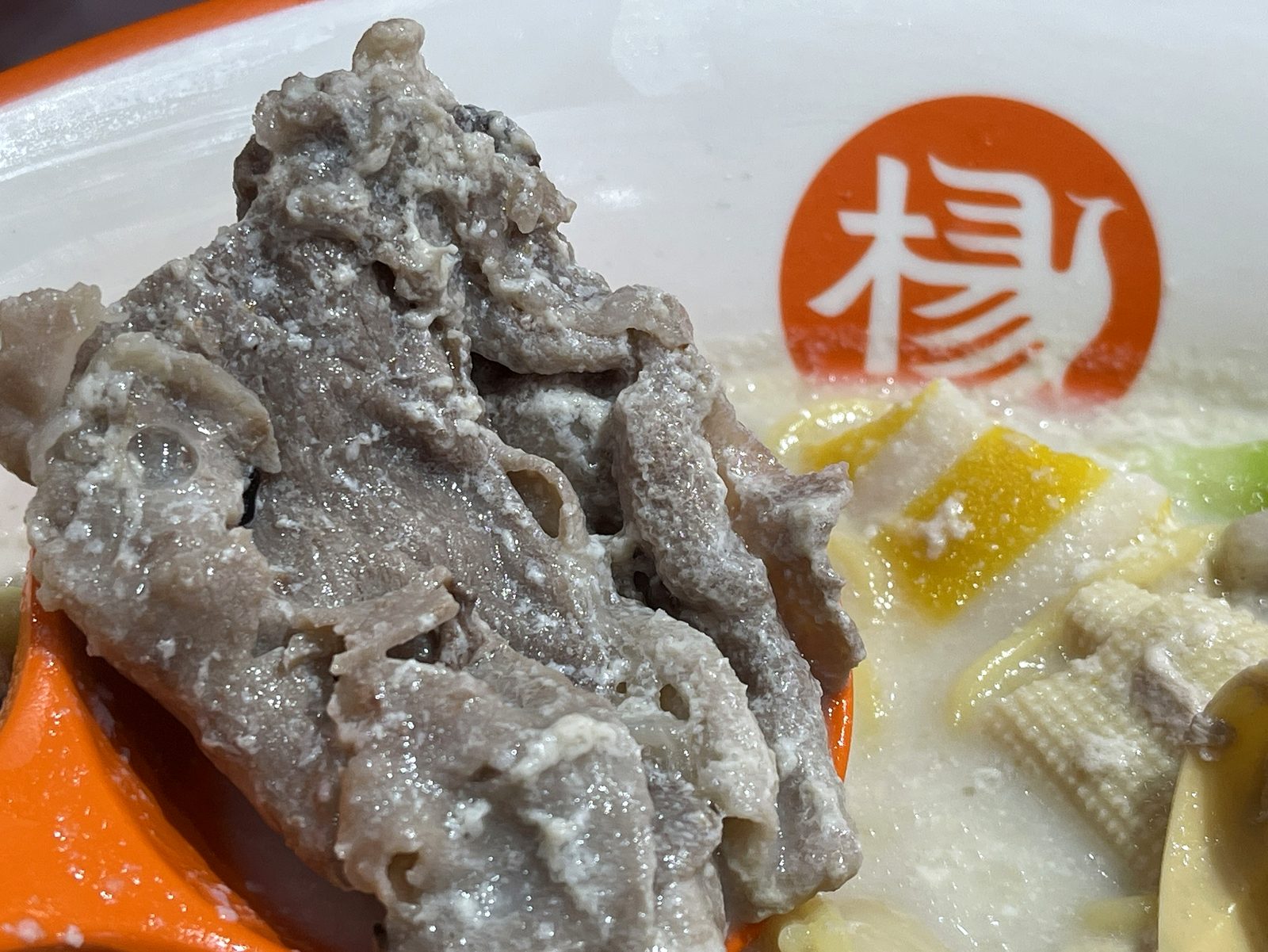 レンゲに乗せた薄切りの牛肉のクローズアップ