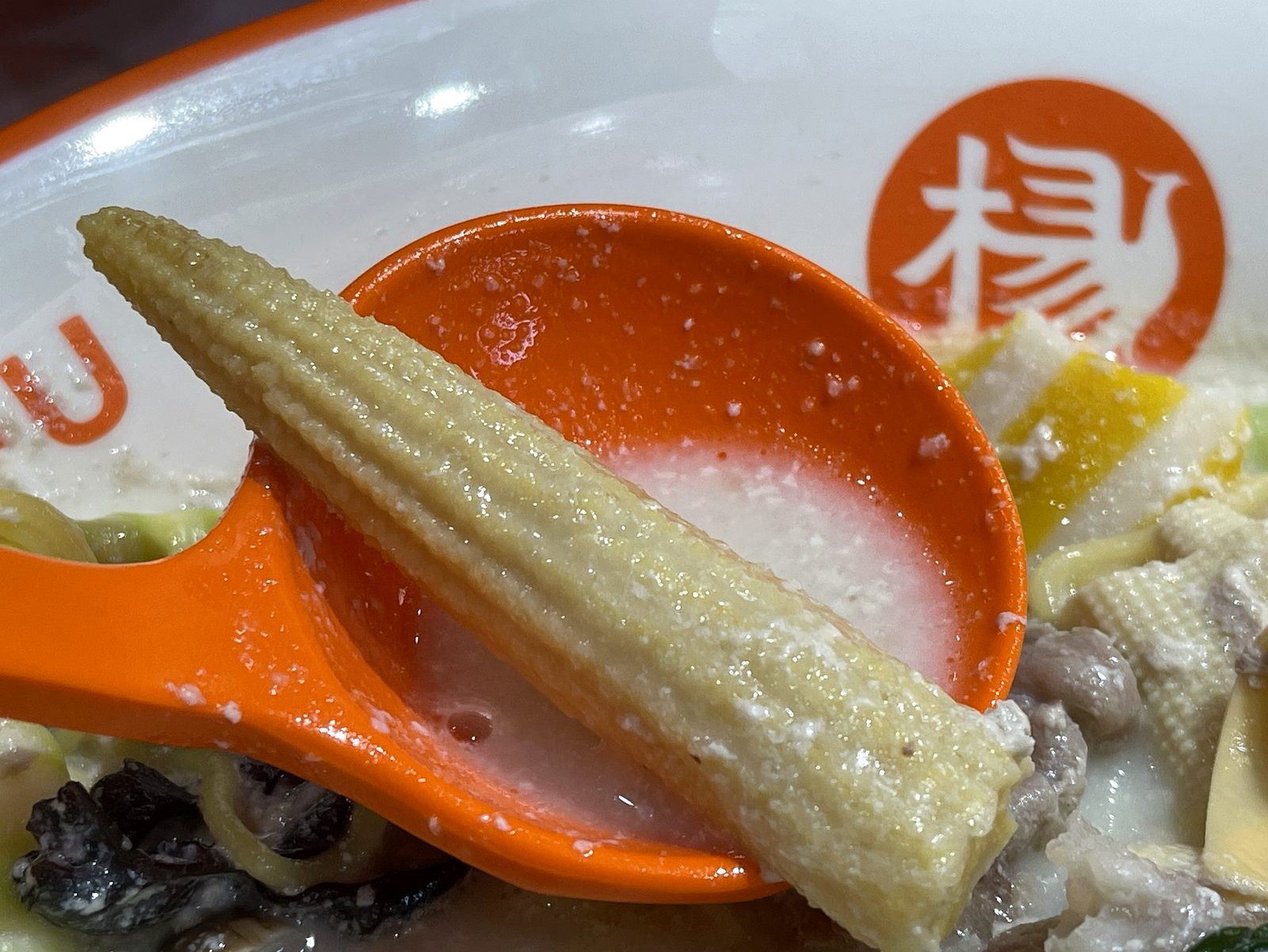 レンゲに乗せたヤングコーン1本のクローズアップ