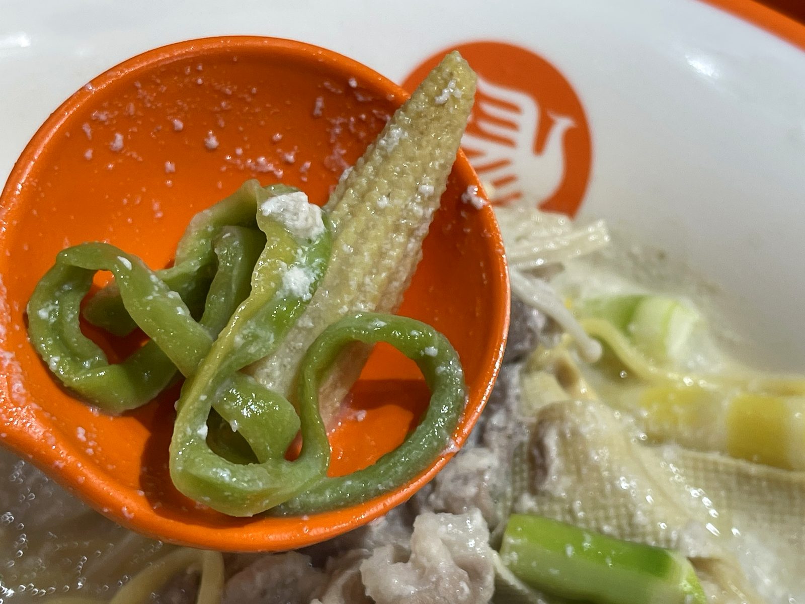 ヤングコーンと緑の野菜を一緒にレンゲに乗せたクローズアップ