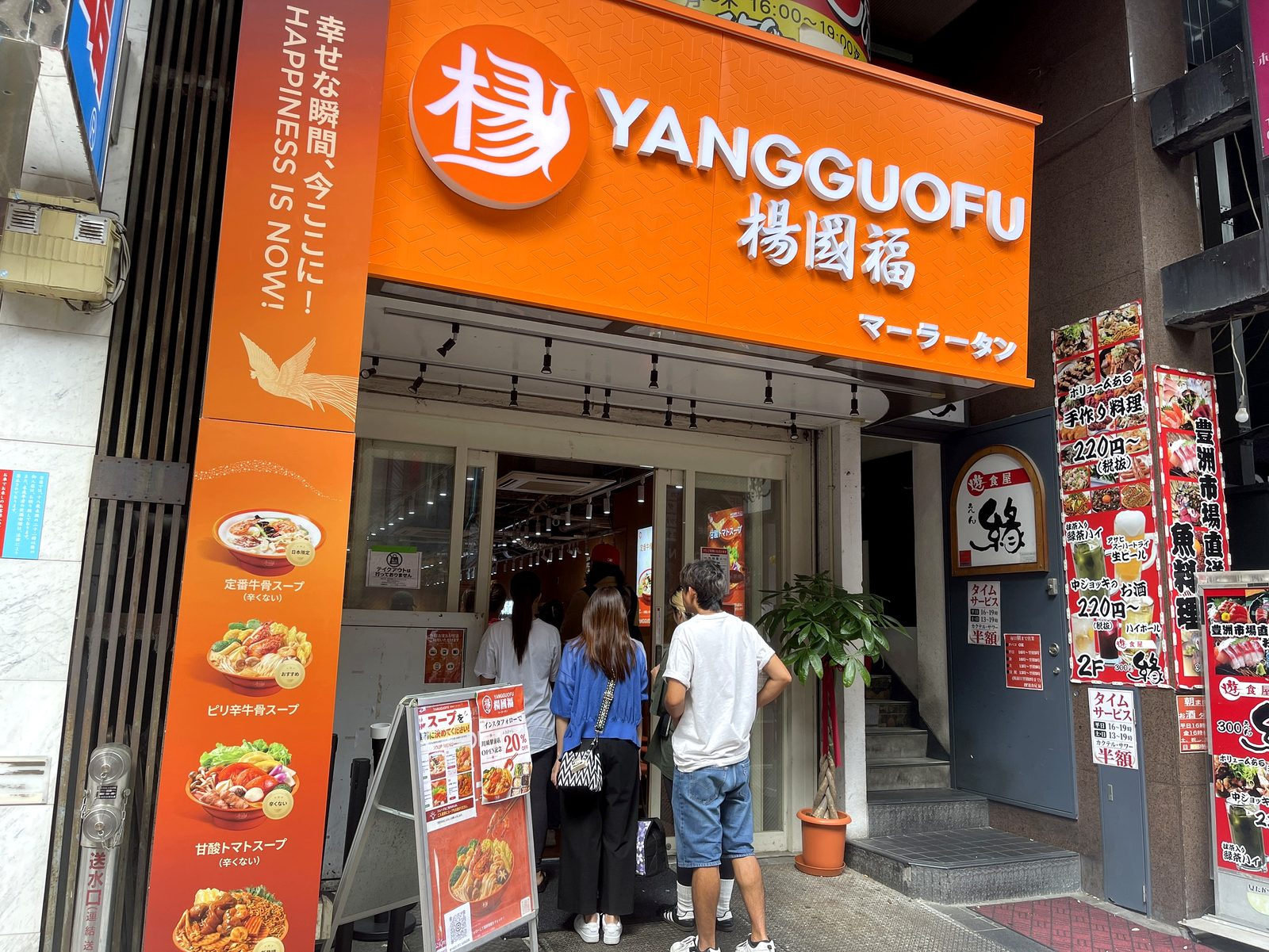 楊國福マーラータン川崎駅前店のオレンジ色の外観と開店前に並ぶ人たち、インスタフォローで20%OFFの立て看板