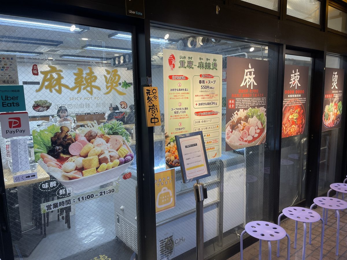 三寅馬重慶麻辣燙の店頭ガラス窓に並ぶ麻辣燙のメニューポスターと椅子