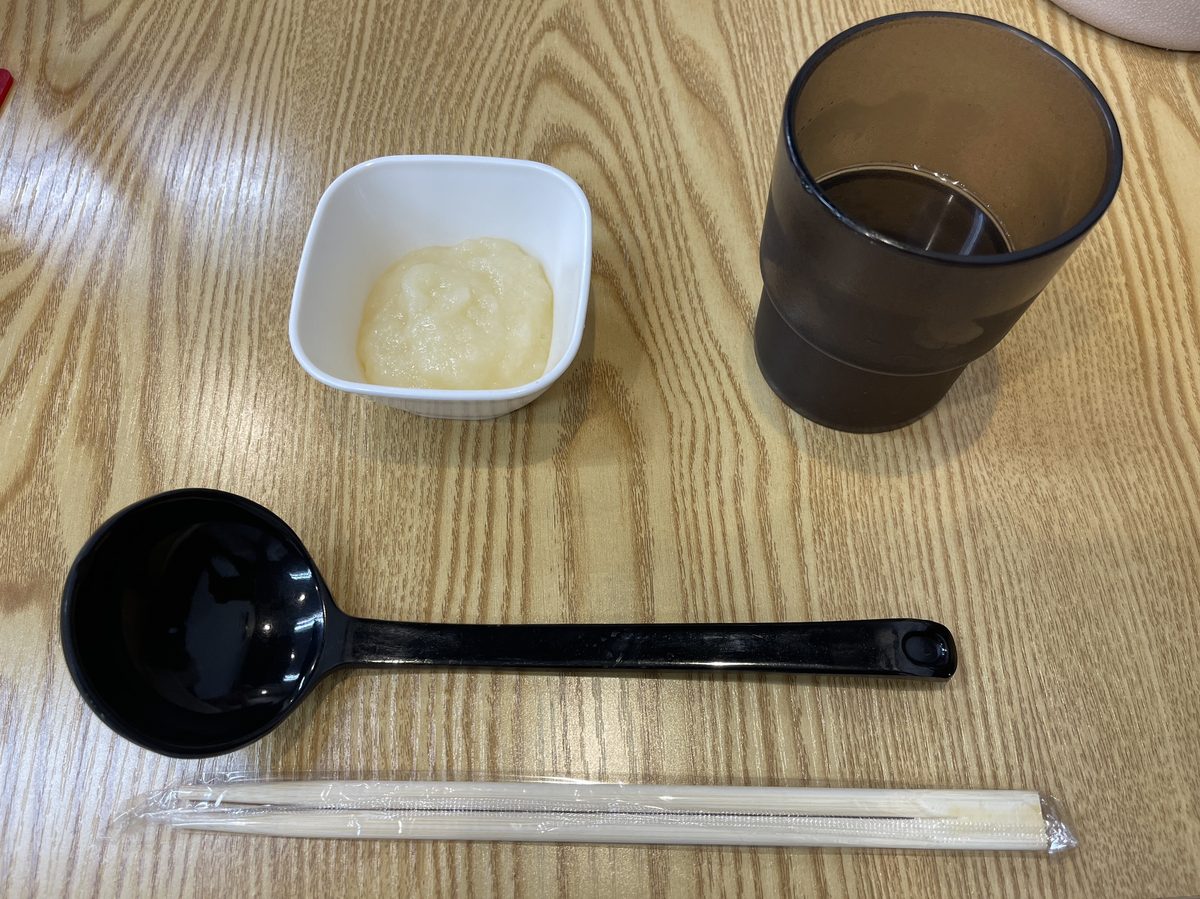 ニンニクをすった薬味とコップと箸が置かれたテーブル