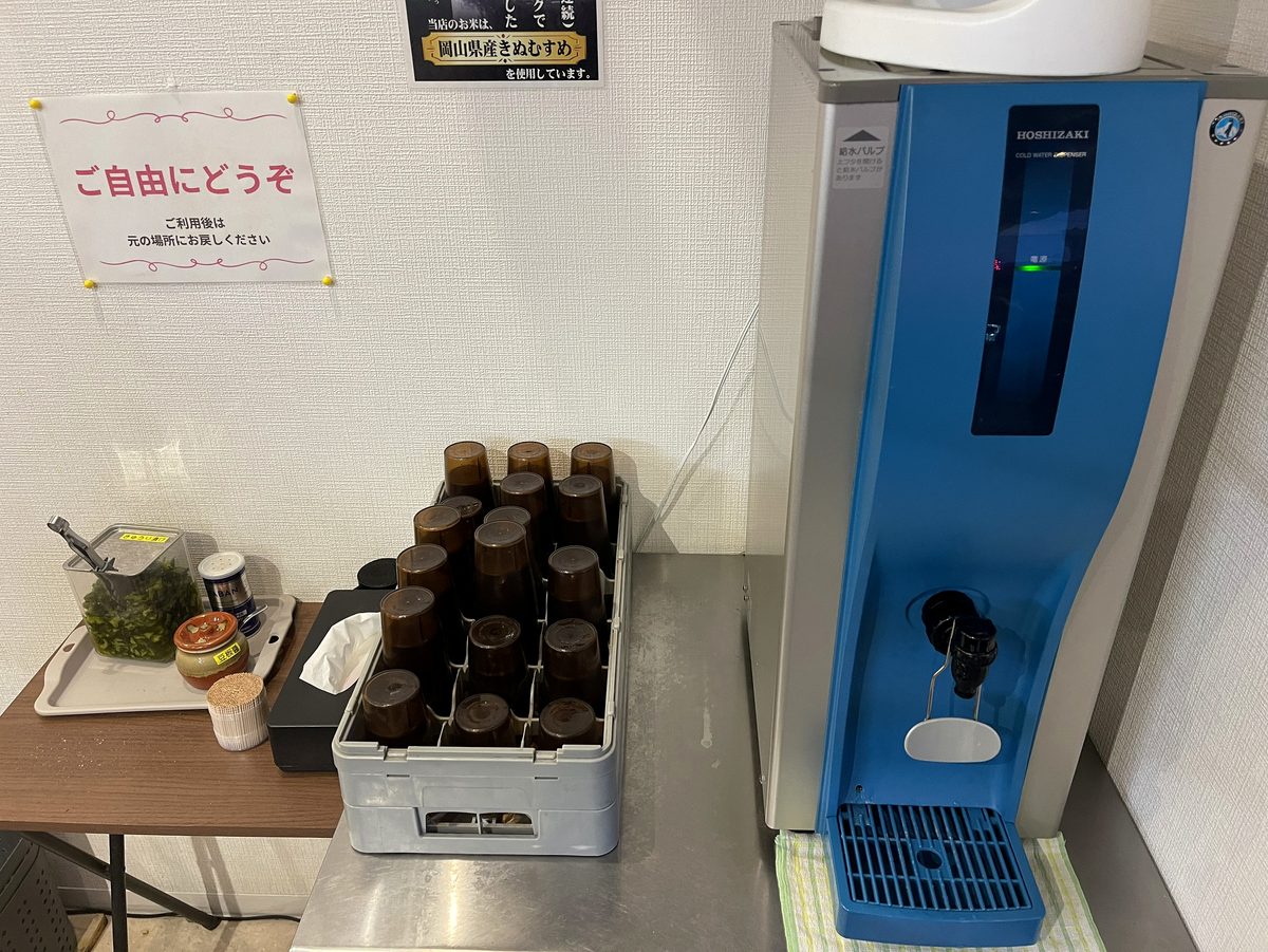 ご自由にどうぞと書かれた給水機と自由に使える刻み高菜などのセルフコーナー