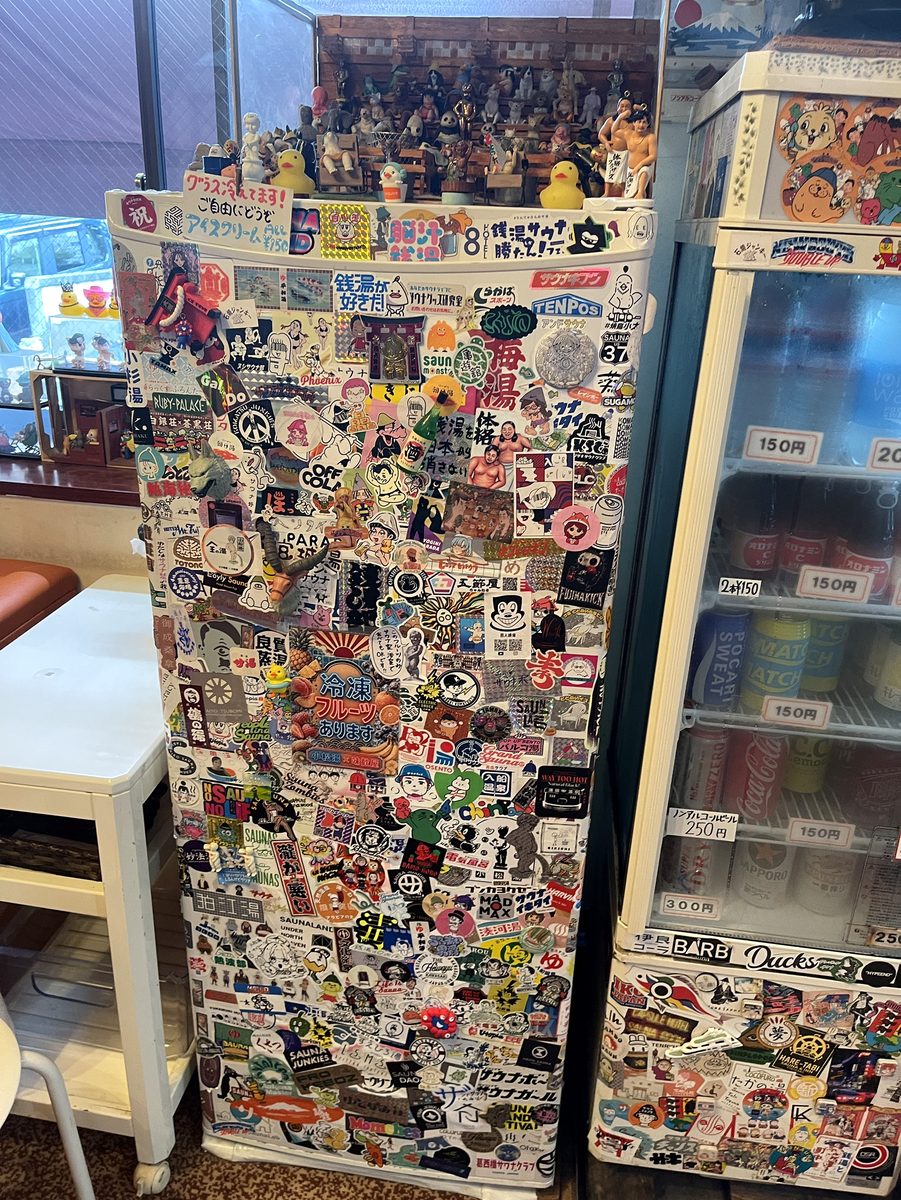 サウナグッズのステッカーがびっしり貼られた小松湯の冷蔵庫