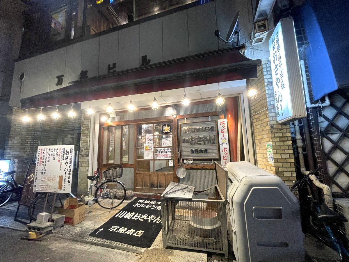 夜の「おさやん!京急川崎本店」の店先、赤ちょうちん系の看板と七輪が見える外観