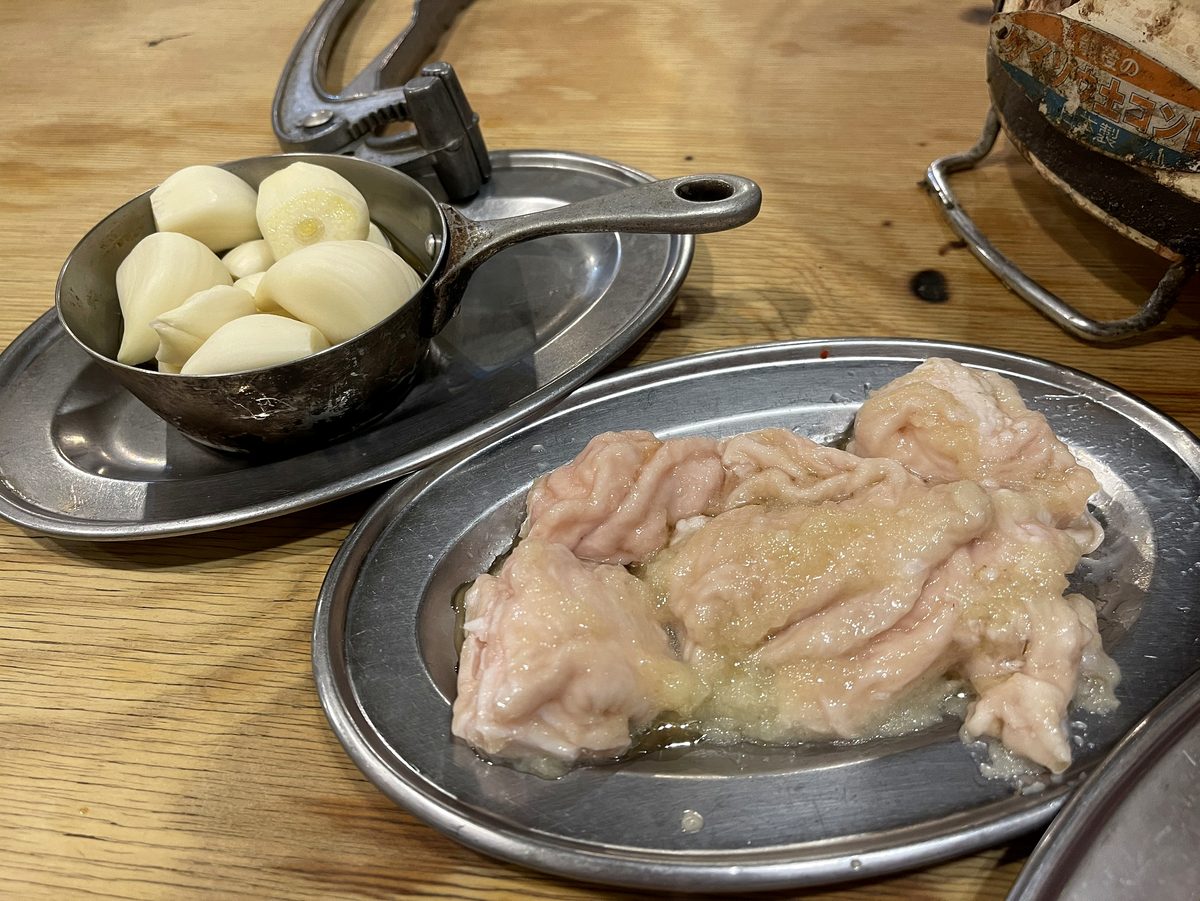 にんにく潰し器とにんにく、その横に生ホルモン1皿