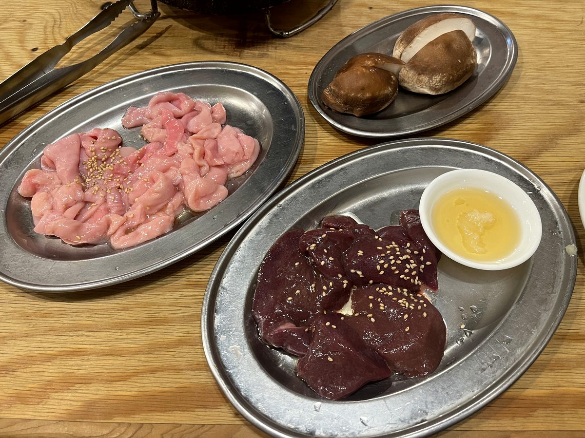 白いホルモンとレバーの生肉2皿、レバーにはごまとおろしにんにくが添えられている