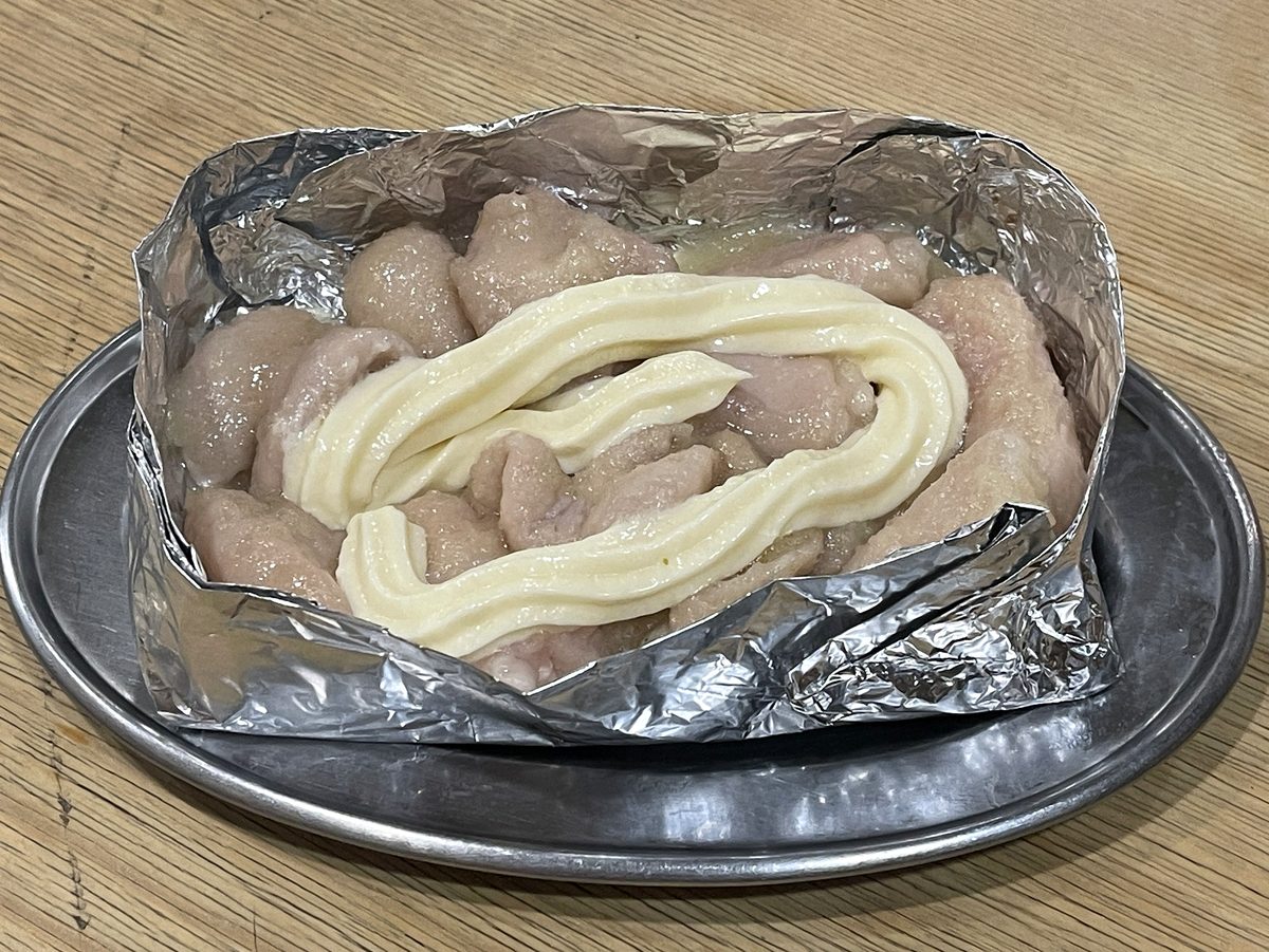 アルミホイルに入ったニンニクたっぷりのホルモンにマヨネーズをかけた一皿