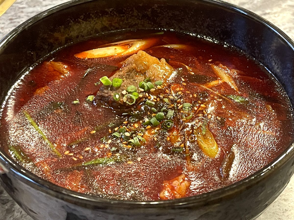 真っ赤なスープに大きなカルビとネギが入った食道園のカルビクッパのアップ