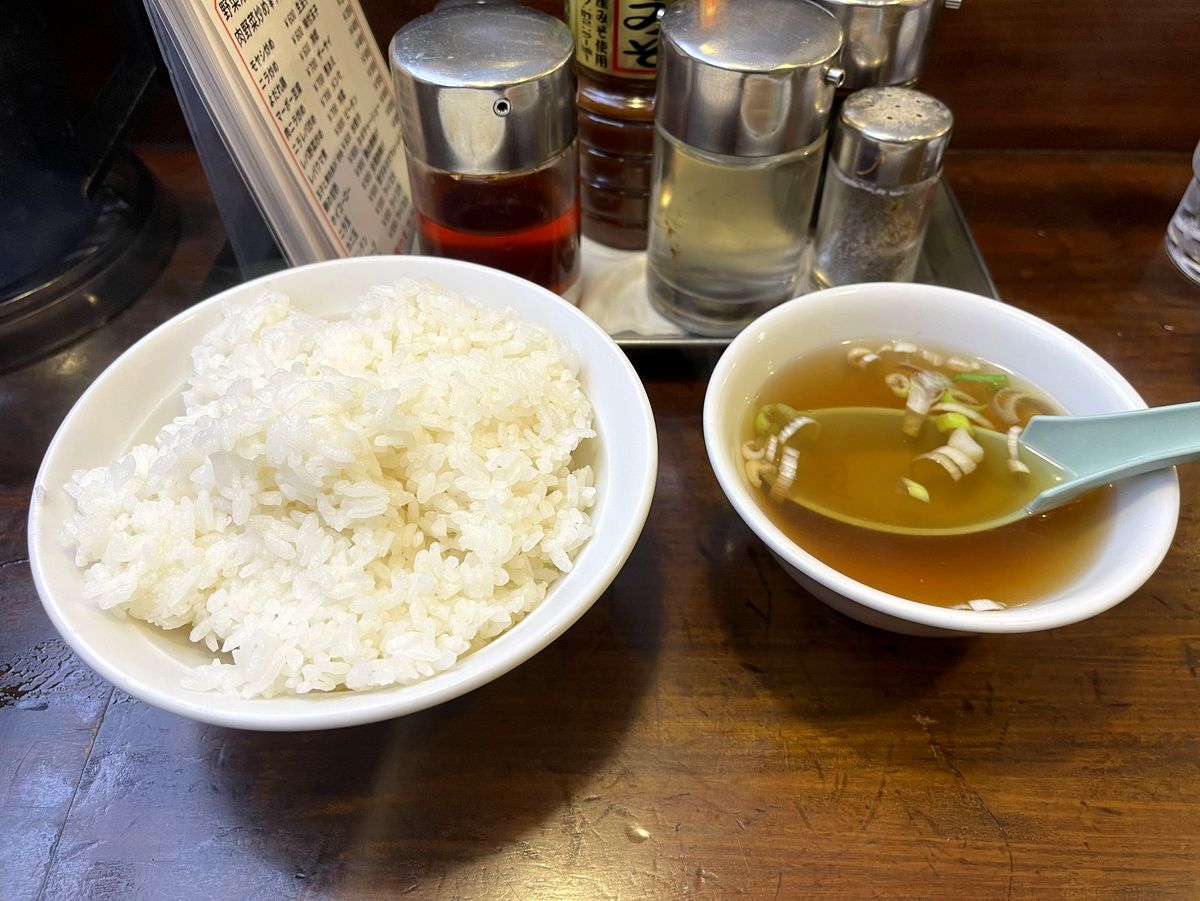 大盛りのライスとスープ、卓上の調味料が並ぶ様子