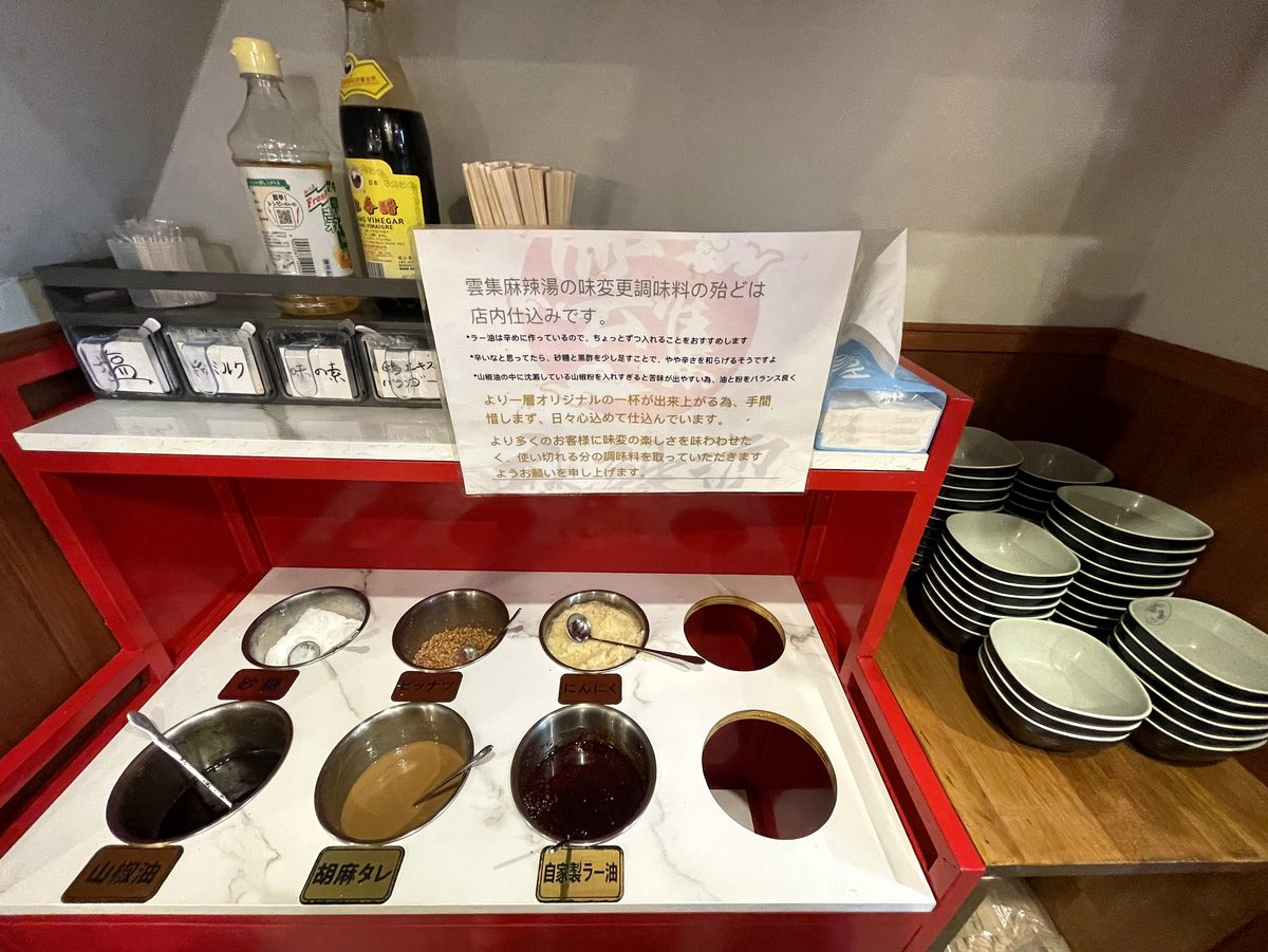 山椒油や胡麻タレ自家製ラー油ニンニクピーナッツ粉ミルクなどが並ぶセルフ調味料コーナー